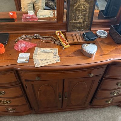 Sale Photo Thumbnail #121: Traditional wooden dresser with attached mirror, displaying assorted items on top including costume jewelry, small collectibles, and paper currency.