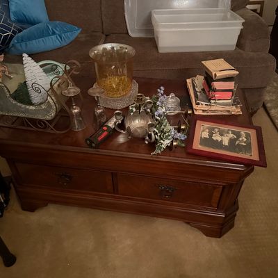 Traditional wooden coffee table featuring front drawers, displayed with an assortment of home decor items including silver-tone...