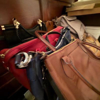Assortment of leather and synthetic women's handbags in various colors including brown, red, black, and navy.