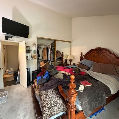 Traditional wooden queen-size four-poster bed frame with carved headboard and detailed posts, paired with a leather-look storage bench at...