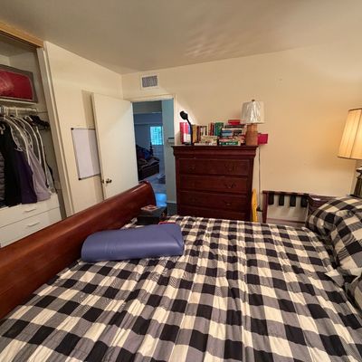 Bedroom set including a wood sleigh bed frame made with black-and-white buffalo plaid bedding, a matching dark wood dresser topped with...