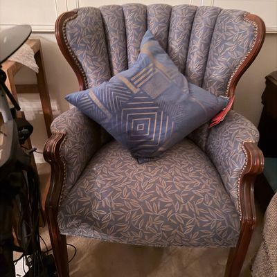 Channel-tufted upholstered armchair with dark wood frame and nailhead trim, paired with a geometric accent pillow.