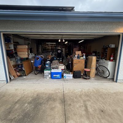 A double garage packed with various household goods, tools, storage bins, a bicycle, and assorted estate sale items.