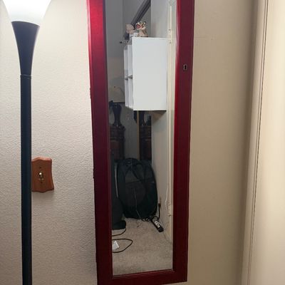 Sale Photo Thumbnail #119: Wall-mounted jewelry armoire cabinet with a full-length mirrored door and a metallic red finish.