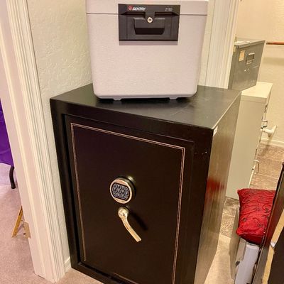 Sale Photo Thumbnail #21: Large black floor safe with digital keypad combination and brass handle, paired with a smaller portable Sentry 2180 fire-resistant safe chest 