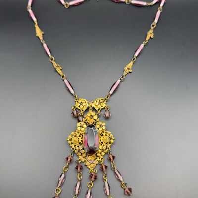 Vintage brass filigree lavalier necklace featuring a large oval purple crystal center and dangling purple glass beads.
