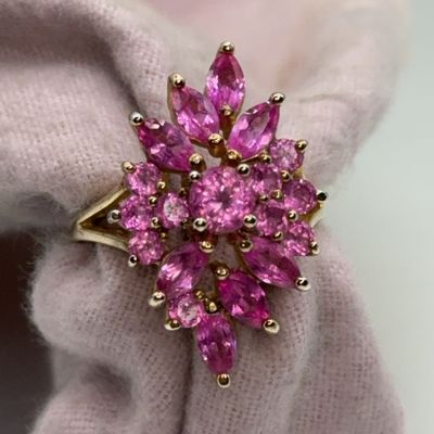 Gold cocktail ring featuring a cluster of round and marquise-cut pink gemstones in a floral sunburst arrangement.