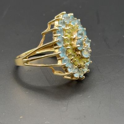 Vintage gold cocktail ring featuring a tiered cluster of round-cut light blue aquamarine or topaz and pale yellow gemstones in a...