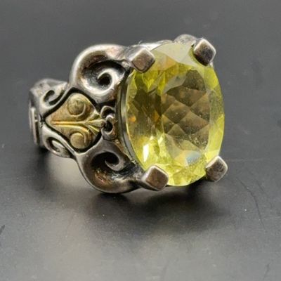 Ornate sterling silver ring featuring a large faceted pale yellow gem set in a four-prong mounting with scrollwork accents.