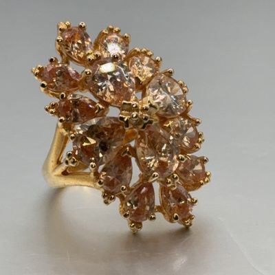 Gold-tone cocktail ring featuring an elaborate cluster of pear-cut and round champagne cubic zirconia or crystal stones.