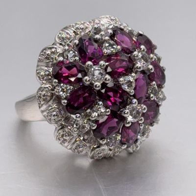Vintage silver cocktail ring featuring a cluster of oval-cut deep purple garnets surrounded by a diamond halo.