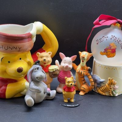 Collection of Disney Winnie the Pooh ceramic and porcelain collectibles, including a large Hunny pot pitcher, small character figurines,...