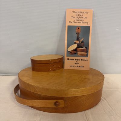 Pair of handcrafted Shaker-style oval bentwood boxes by Rosie, featuring a smaller fingered oval box stacked atop a large handled carrier...