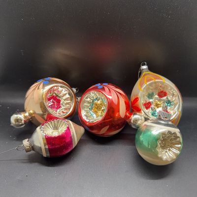 Collection of five vintage glass Christmas ornaments featuring colorful indent designs, hand-painted details, and silvered interiors,...