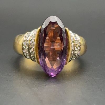 Gold cocktail ring featuring a large marquise-cut amethyst or ametrine center stone flanked by pave-set diamond accent shoulders.