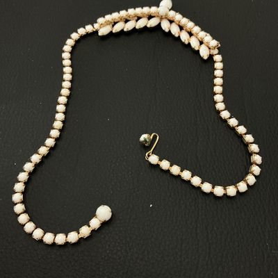 Sale Photo Thumbnail #233: A vintage gold-tone statement choker necklace featuring opaque white milk glass or Lucite marquise and round cabochons in a central floral/leaf pattern with a rhinestone strand. Features a J-hook clasp closure. Measures approximately 15 to 16 inches in to