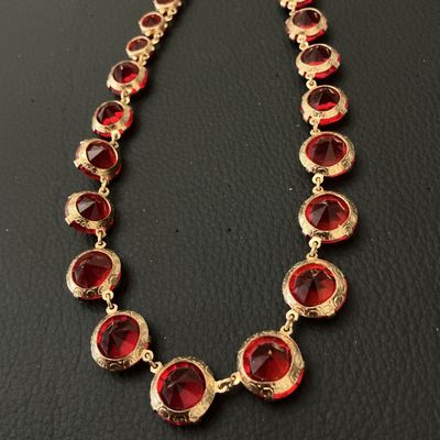 Sale Photo Thumbnail #211: Vintage gold-tone choker necklace featuring round, prong-set vibrant red rhinestones or glass crystals with decorative textured settings. Includes an adjustable hook closure with a rhinestone dangle tail. Appears to be in good vintage condition with all s
