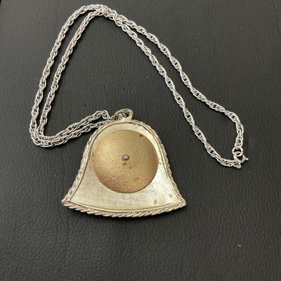 Sale Photo Thumbnail #198: A vintage silver-tone rope chain necklace featuring a bell-shaped pendant with a green enamel border and a central round medallion depicting the Sagittarius archer/cherub with a bow and arrow. Pendant measures approximately 60mm wide by 60mm tall. Shows l