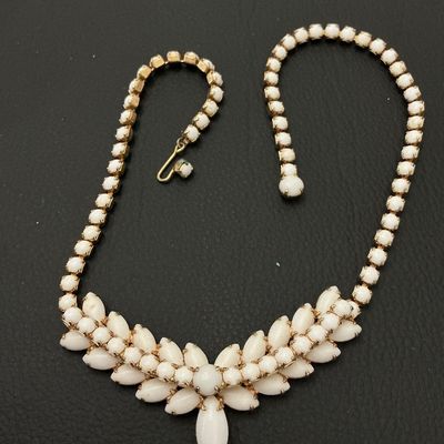 Sale Photo Thumbnail #232: A vintage gold-tone statement choker necklace featuring opaque white milk glass or Lucite marquise and round cabochons in a central floral/leaf pattern with a rhinestone strand. Features a J-hook clasp closure. Measures approximately 15 to 16 inches in to