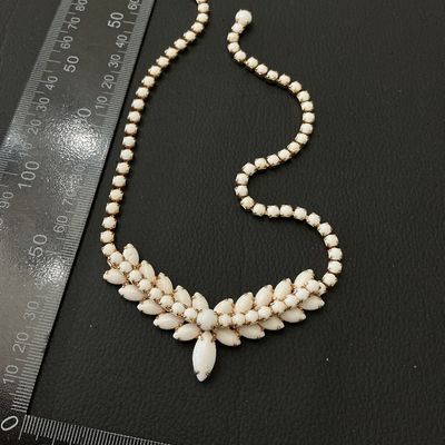 Sale Photo Thumbnail #234: A vintage gold-tone statement choker necklace featuring opaque white milk glass or Lucite marquise and round cabochons in a central floral/leaf pattern with a rhinestone strand. Features a J-hook clasp closure. Measures approximately 15 to 16 inches in to
