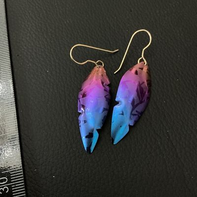 Sale Photo Thumbnail #235: Pair of iridescent leaf or feather-shaped dangle drop earrings featuring vibrant purple, pink, and blue anodized finish with a leaf pattern design. Fitted with wire shepherd hooks. Excellent condition with bright coloring and minimal signs of wear. Each d