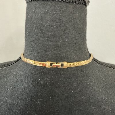 Sale Photo Thumbnail #220: Vintage gold-tone herringbone flat chain collar necklace featuring a central diamond-shaped focal point set with clear triangular rhinestones. Stamped S.A.L. © on the back (Swarovski America Limited mark used circa late 1970s to 1980s). Features a fold-o