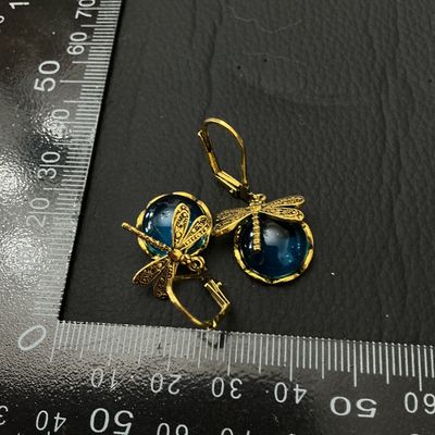 Sale Photo Thumbnail #192: Pair of gold-tone leverback drop earrings featuring a dragonfly accent seated atop round teal-blue glass cabochons. Total length is approximately 35 mm (1.4 inches). Good condition with minor surface wear on metal backs.