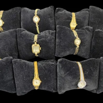 Sale Photo Thumbnail #47: Collection of twelve vintage women's gold-tone wristwatches displayed on black velvet cushions.