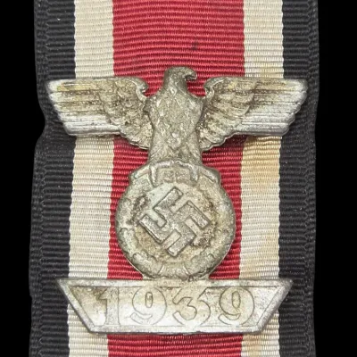 Sale Photo Thumbnail #142: World War II German 1939 Iron Cross 2nd Class spange attached to a original tri-color ribbon, showing heavy patina and wear.
