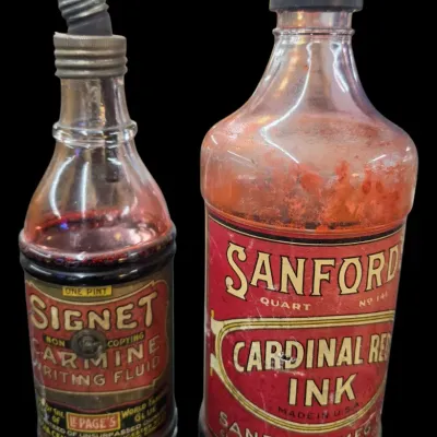 Sale Photo Thumbnail #36: Pair of vintage glass ink bottles, including a Signet Carmine Writing Fluid pint bottle and a Sanford's Cardinal Red Ink quart bottle, both featuring original paper labels and metal pour spouts.