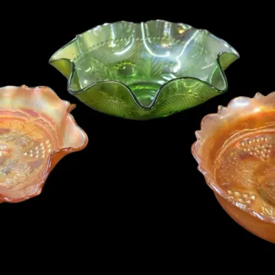 Sale Photo Thumbnail #101: Trio of vintage iridescent carnival glass bowls with ruffled and scalloped rims, featuring embossed grape and vine designs in marigold and green shades.