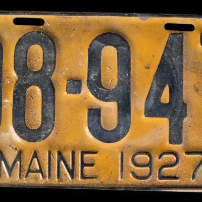Sale Photo Thumbnail #64: Vintage 1927 Maine license plate featuring black embossed numbers and text on an orange background, showing age-appropriate patina and wear.