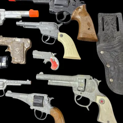 Sale Photo Thumbnail #161: Collection of vintage die-cast metal cap guns and a tooled leather holster, including Hubley and Texan Jr. models.