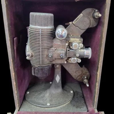 Sale Photo Thumbnail #88: Vintage Keystone 8mm movie projector, housed in its original velvet-lined carrying case, showing age-appropriate surface wear and patina.