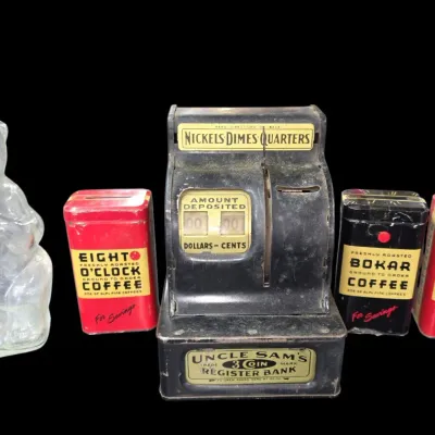 Sale Photo Thumbnail #153: Collection of vintage toy banks, including an Uncle Sam's 3 Coin Register Bank, a clear glass bear bank, and three A&P coffee tin banks.