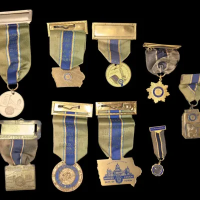 Sale Photo Thumbnail #157: Collection of mid-20th-century vintage American Legion convention medals and ribbon badges, featuring state and departmental designs from Massachusetts and Iowa.