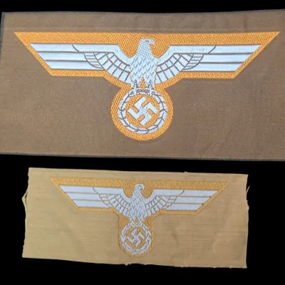 Sale Photo Thumbnail #129: Two World War II era German military breast eagle cloth patches, featuring machine-embroidered eagles atop swastika insignias on tan and light brown fabric backing.
