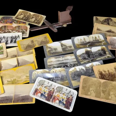 Sale Photo Thumbnail #97: Antique wooden stereoscope viewer accompanied by a collection of antique stereoview cards depicting landscape scenes and portraits.