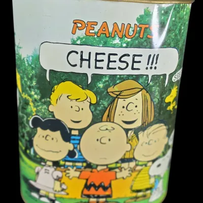 Sale Photo Thumbnail #65: Vintage Peanuts metal trash can featuring Charlie Brown, Lucy, Schroeder, Peppermint Patty, Linus, Snoopy, and Woodstock saying "CHEESE!!!".