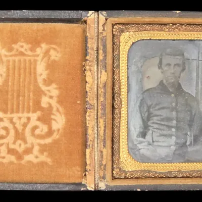 Sale Photo Thumbnail #135: 19th-century cased tintype or daguerreotype portrait of a seated man, housed in an ornate gilt frame and velvet-lined folding case.