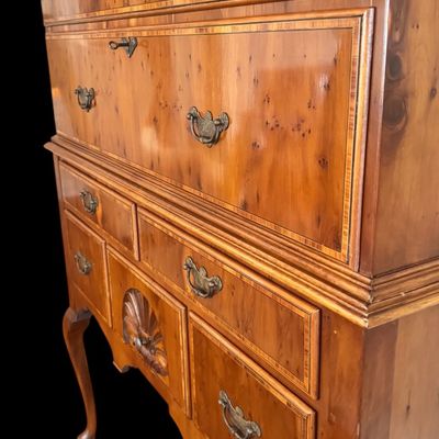 Sale Photo Thumbnail #102: This exquisite Queen Anne style highboy features a classic bonnet-top (or swan's neck) pediment adorned with a central carved shell motif and finials. The piece is constructed with rich, figured walnut veneers, showcasing intricate grain patterns across t