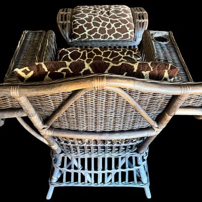 Sale Photo Thumbnail #292: Constructed from woven wicker and rattan, featuring a distinctive, wide-arm design with an integrated circular cup holder on the right armrest. The chair is upholstered in bold, animal-print fabric featuring a giraffe-inspired pattern. Its structural comp