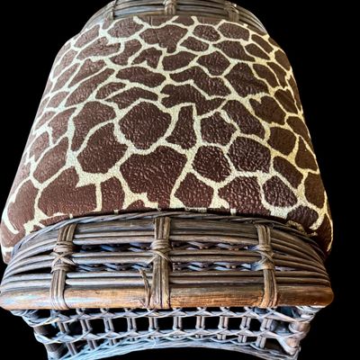 Sale Photo Thumbnail #294: Constructed from woven wicker and rattan, featuring a distinctive, wide-arm design with an integrated circular cup holder on the right armrest. The chair is upholstered in bold, animal-print fabric featuring a giraffe-inspired pattern. Its structural comp