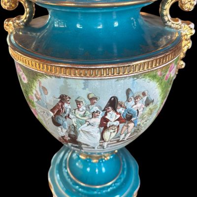Sale Photo Thumbnail #247: This large decorative French urn features a vibrant teal glazed neck and base, accented with ornate gilded details and handles. The body is decorated with a detailed, hand painted 18th century courting scene. Neo classical design from the late 19th/early 