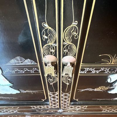 Sale Photo Thumbnail #180: A large black lacquer and mother-of-pearl inlaid figural sideboard depicting the popular “Royal Ladies” narrative scene. Constructed with four central cabinet doors and four upper drawers. The craftsmanship reflects the traditional East Asian furnitur