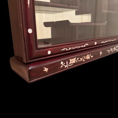 Sale Photo Thumbnail #194: Exquisite wall-mounted curio cabinet, often referred to as a “bogu” shelf constructed from dense rosewood and features intricate beautiful mother-of-pearl inlay. The frame is adorned with delicate floral and avian motifs and enclosed by a glass-fronte