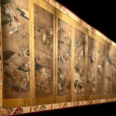 Sale Photo Thumbnail #3: Impressive Japanese eight-panel folding screen featuring hand painted narrative scenes of figures in traditional dress, architecture, and landscapes in muted earth tones with colorful accents. The paintings are framed by gold tone borders, decorative silk