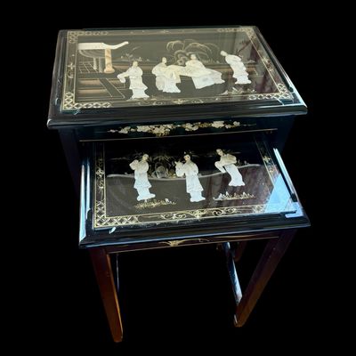 Sale Photo Thumbnail #171: Vintage Chinese nesting tables featuring a deep black lacquer finish with intricate applied porcelain figurines. Each table top is protected with a glass insert depicting East Asian scenes. The tables are constructed with clean, minimalist lines typical o