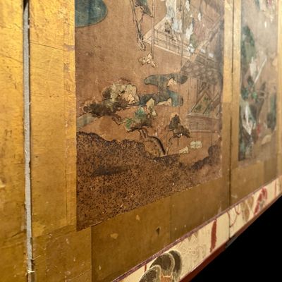Sale Photo Thumbnail #7: Impressive Japanese eight-panel folding screen featuring hand painted narrative scenes of figures in traditional dress, architecture, and landscapes in muted earth tones with colorful accents. The paintings are framed by gold tone borders, decorative silk