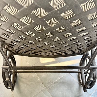 Sale Photo Thumbnail #284: This  pair of vintage chaise lounges features a durable cast aluminum frame finished in a matte black powder coat, characterized by intricate, lattice-style openwork on the frame and legs. This piece is mounted on two functional wheels, facilitating easy 